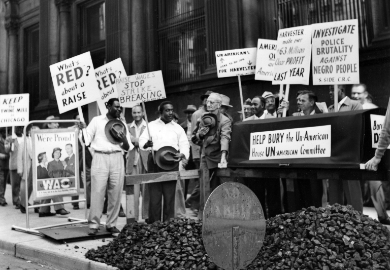 A group of striking International Harvester workers, Black and white, holding signs denouncing the House Un-American Activities Committee