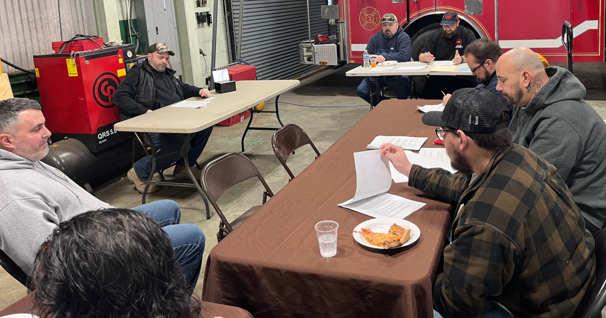 A group of UE members sitting around a table discussing their contract settlement