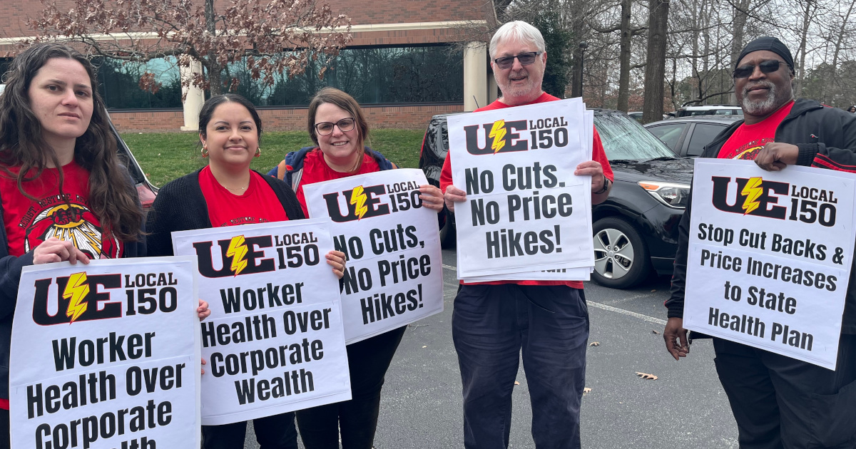 Five workers with signs reading Worker Health Over Corporate Wealth and No Cuts, No Price Hikes