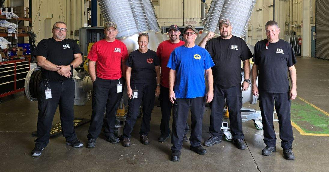 Seven UE members wearing union t-shirts on the shop floor